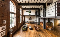 Warehouse conversion with beams, mezzanine floor, arched windows and exposed brick.